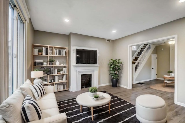 living room featuring stairway, visible vents, wood finished floors, and a fireplace