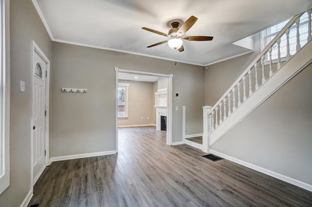 interior space with wood finished floors, baseboards, ornamental molding, and a fireplace