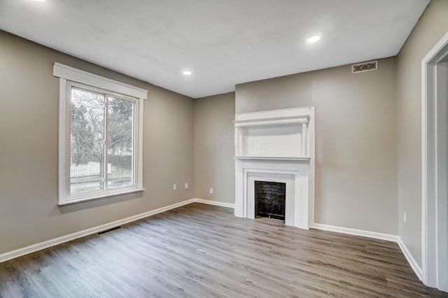 unfurnished living room with a fireplace, visible vents, and baseboards