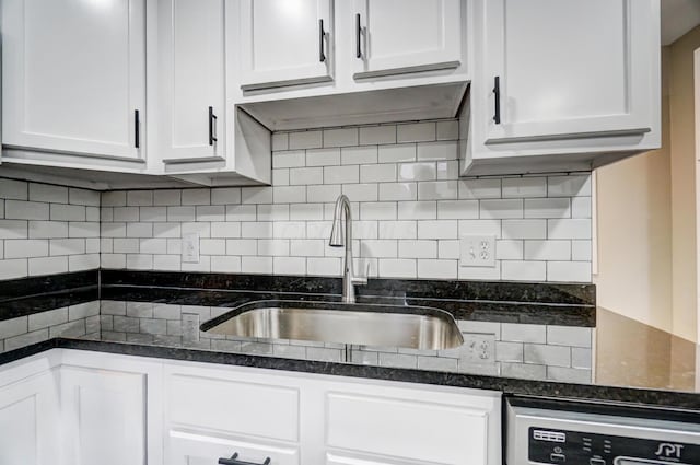 kitchen with backsplash, dishwasher, dark stone countertops, white cabinets, and a sink