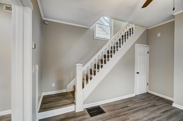 stairway with wood finished floors, visible vents, and ornamental molding