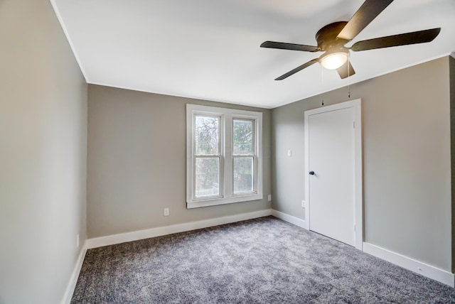 carpeted spare room featuring a ceiling fan and baseboards