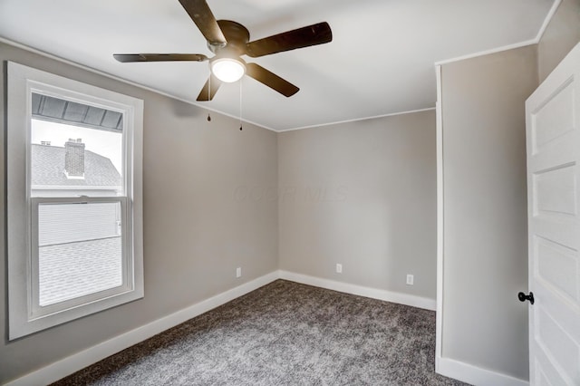 empty room featuring baseboards, dark carpet, and ceiling fan