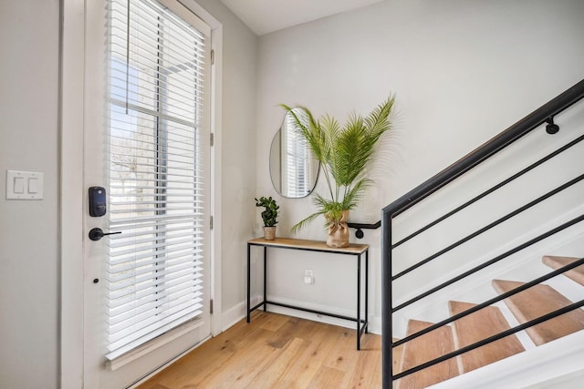 foyer entrance with light wood-type flooring, baseboards, and stairs