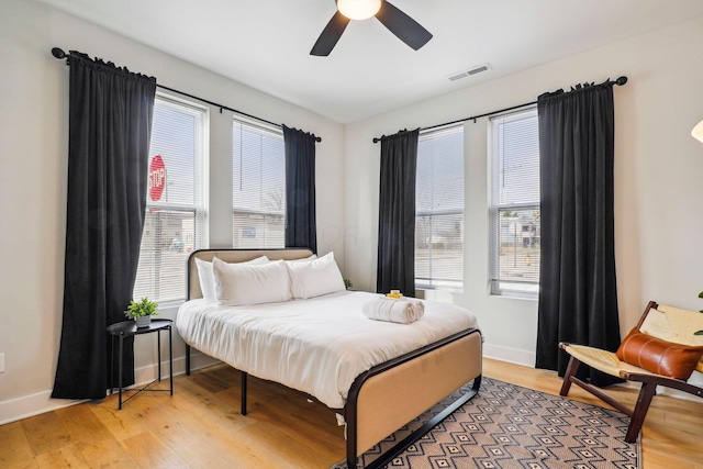 bedroom with visible vents, multiple windows, light wood-type flooring, and baseboards