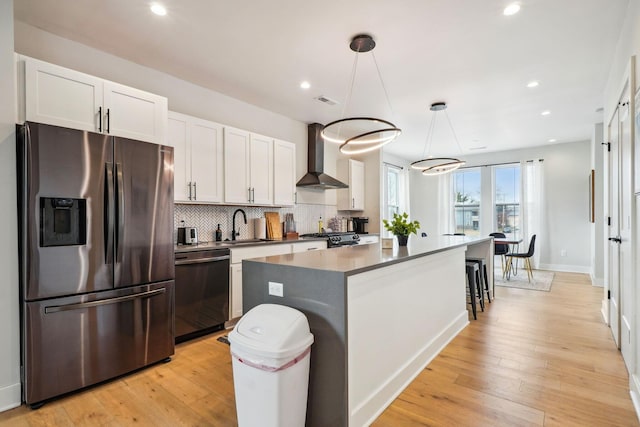 kitchen with backsplash, a center island, wall chimney range hood, stainless steel appliances, and a sink