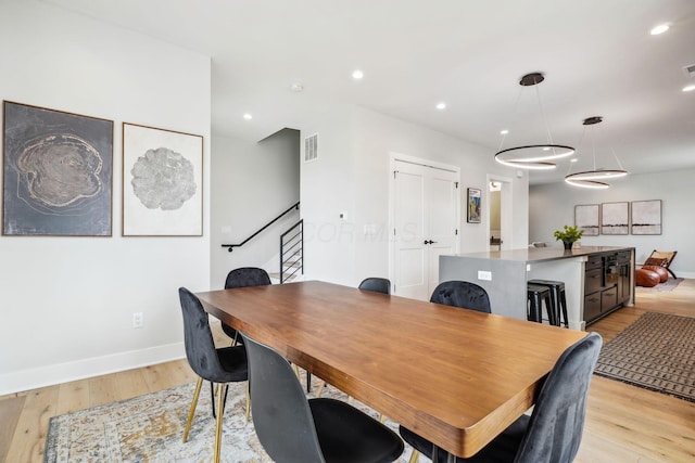 dining space with recessed lighting, light wood-style floors, and stairs