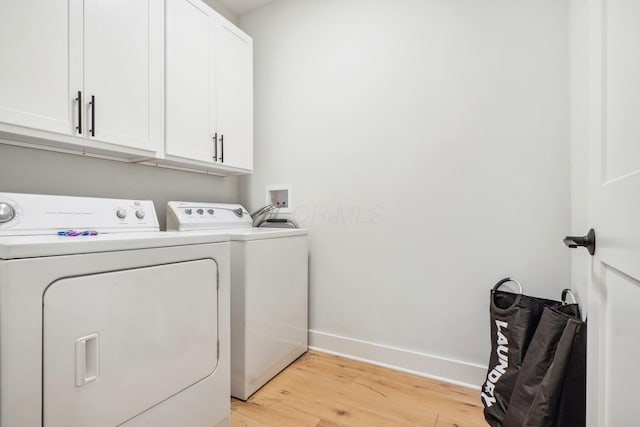 laundry room featuring cabinet space, light wood-type flooring, independent washer and dryer, and baseboards