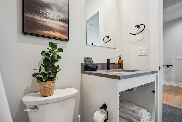 bathroom with baseboards, toilet, wood finished floors, and vanity