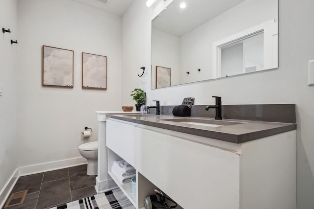 full bath featuring double vanity, toilet, baseboards, and a sink