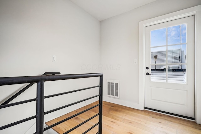 doorway with baseboards, visible vents, and light wood finished floors