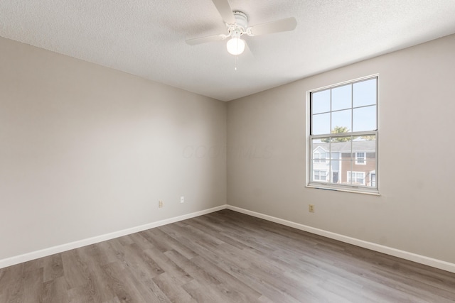 empty room with a ceiling fan, wood finished floors, baseboards, and a textured ceiling