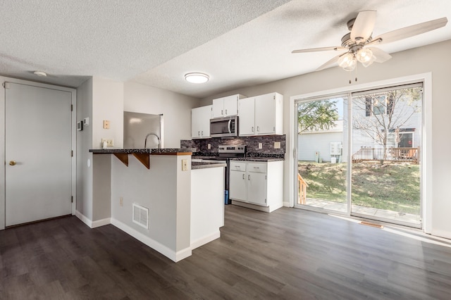 kitchen featuring dark countertops, visible vents, a peninsula, and stainless steel appliances