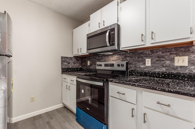 kitchen featuring backsplash, white cabinetry, stainless steel appliances, light wood-style floors, and a textured ceiling