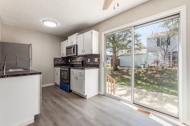 kitchen featuring visible vents, a sink, white cabinetry, appliances with stainless steel finishes, and decorative backsplash