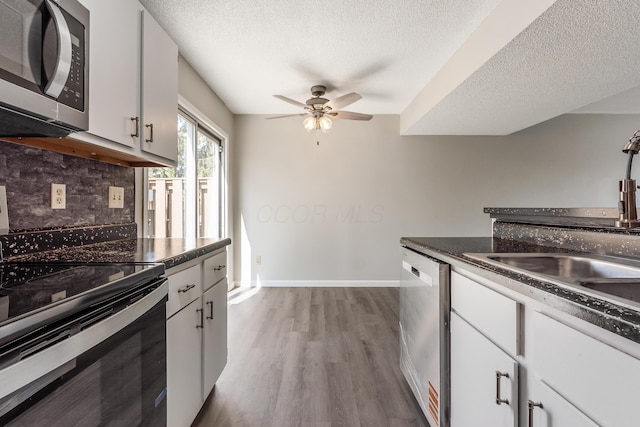 kitchen featuring dark countertops, backsplash, wood finished floors, and appliances with stainless steel finishes