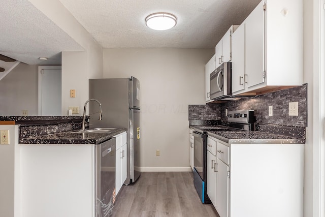 kitchen featuring a sink, backsplash, stainless steel appliances, white cabinets, and light wood finished floors