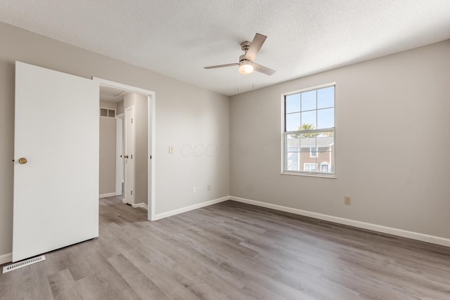 spare room with visible vents, a textured ceiling, and wood finished floors