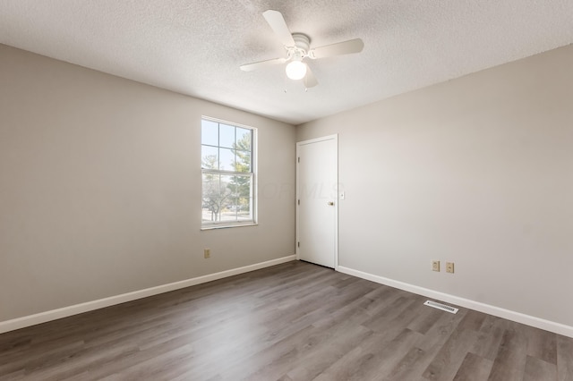 unfurnished room with visible vents, a ceiling fan, a textured ceiling, wood finished floors, and baseboards