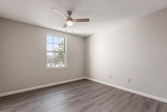 unfurnished room with ceiling fan, a textured ceiling, baseboards, and wood finished floors