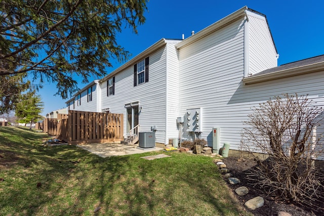 rear view of property featuring a patio, a lawn, fence, and central AC