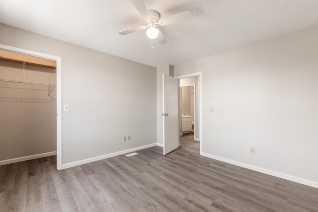 unfurnished bedroom featuring a textured ceiling, wood finished floors, a closet, baseboards, and ceiling fan