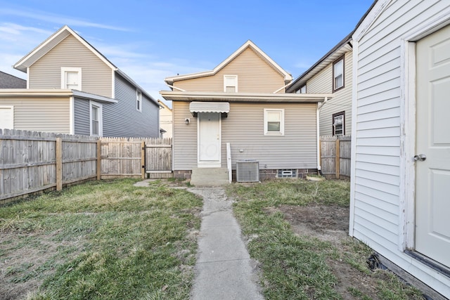 back of property featuring central air condition unit, a lawn, and a fenced backyard