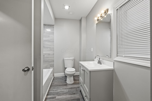 full bath featuring a tub, baseboards, toilet, wood finished floors, and vanity