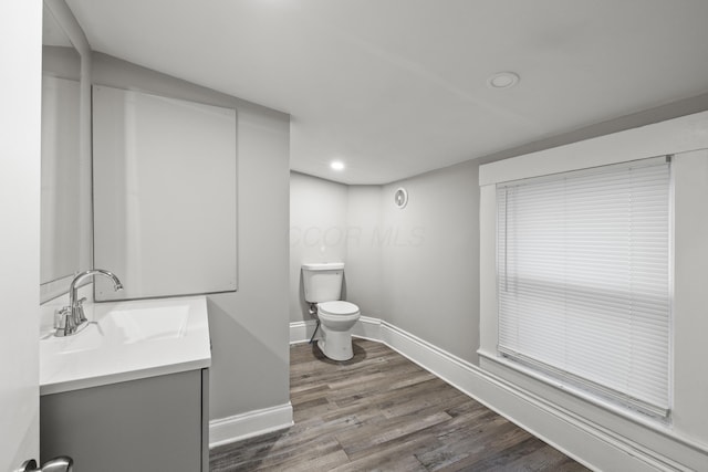 bathroom featuring baseboards, toilet, wood finished floors, and vanity