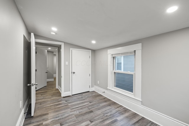 unfurnished bedroom featuring recessed lighting, baseboards, lofted ceiling, and wood finished floors