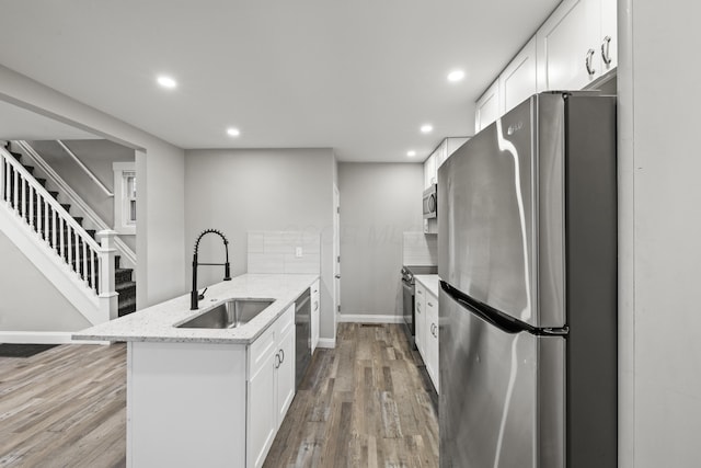 kitchen with wood finished floors, recessed lighting, a sink, appliances with stainless steel finishes, and white cabinetry