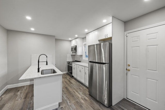 kitchen with dark wood-style floors, a sink, appliances with stainless steel finishes, white cabinetry, and backsplash