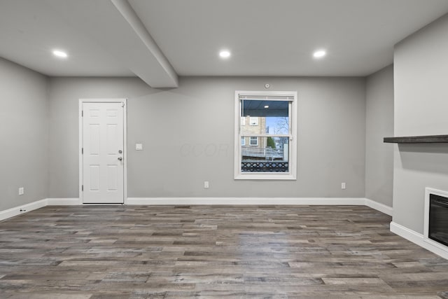 unfurnished living room featuring recessed lighting, wood finished floors, and baseboards