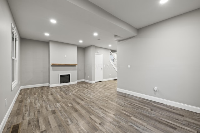 unfurnished living room featuring visible vents, baseboards, recessed lighting, a fireplace, and wood finished floors