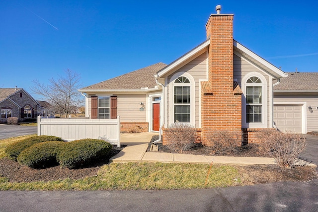 view of front of property featuring fence, roof with shingles, a chimney, a garage, and brick siding