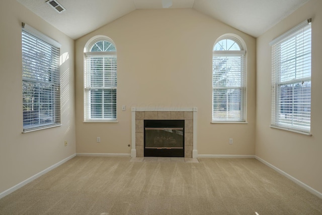 unfurnished living room with visible vents, baseboards, a fireplace, vaulted ceiling, and carpet flooring