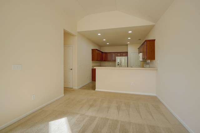 interior space with white refrigerator with ice dispenser, a peninsula, light countertops, light colored carpet, and vaulted ceiling