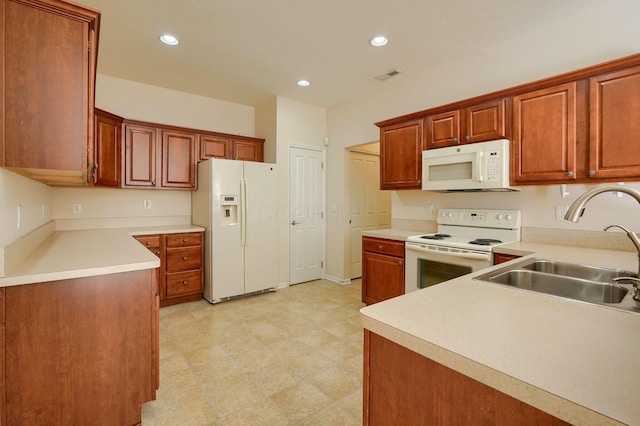 kitchen featuring recessed lighting, white appliances, light countertops, and a sink