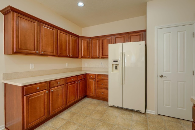 kitchen with recessed lighting, brown cabinets, white fridge with ice dispenser, and light countertops