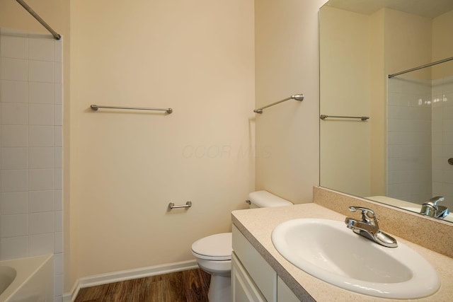 full bath with toilet, shower / tub combination, wood finished floors, baseboards, and vanity