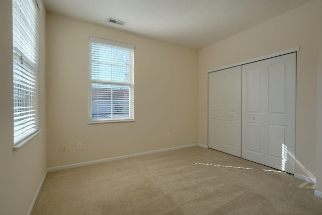 unfurnished bedroom featuring visible vents, baseboards, a closet, and carpet flooring