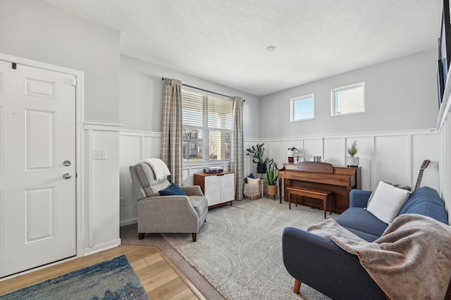 sitting room with plenty of natural light, a textured ceiling, and light wood-style floors