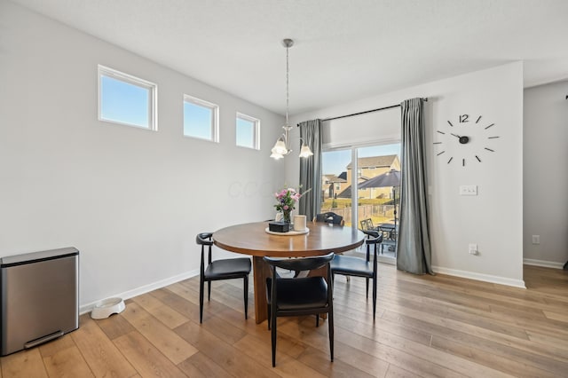 dining room featuring light wood-style flooring, an inviting chandelier, and baseboards