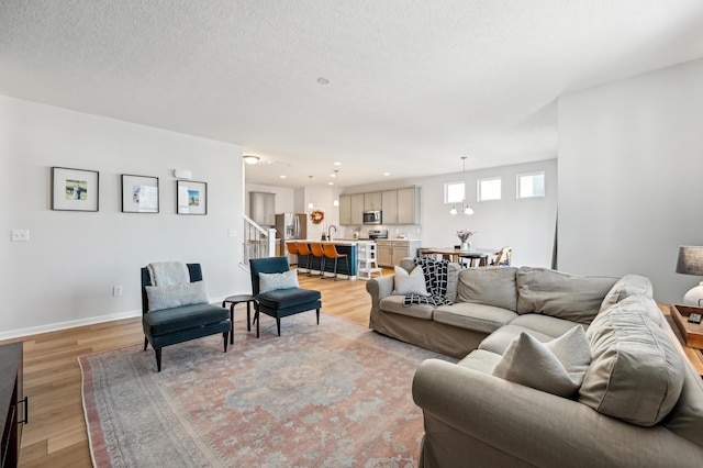 living area with baseboards, stairs, recessed lighting, light wood-style floors, and a textured ceiling