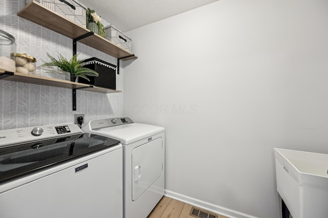 laundry area with visible vents, baseboards, washer and clothes dryer, laundry area, and light wood-style flooring