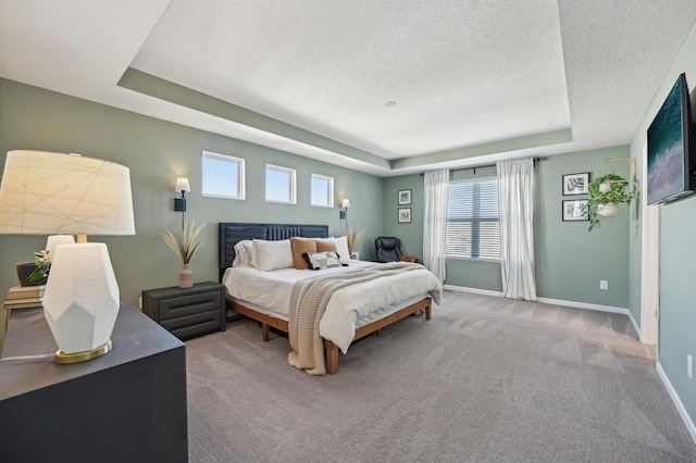 bedroom with a tray ceiling, carpet, baseboards, and a textured ceiling