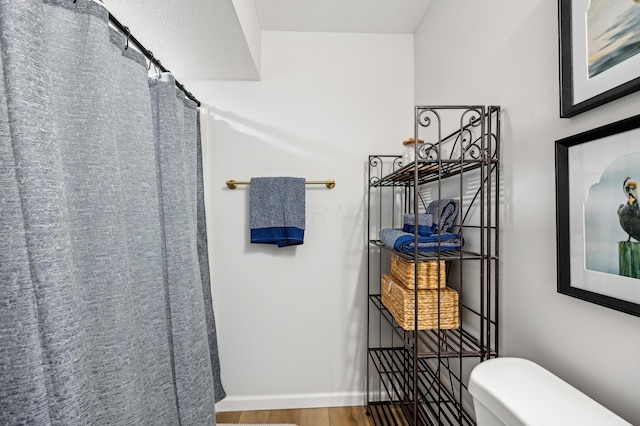 full bathroom with a shower with shower curtain, toilet, wood finished floors, and baseboards