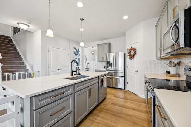 kitchen with a sink, backsplash, appliances with stainless steel finishes, and gray cabinetry