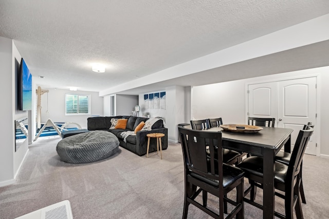 dining room featuring light colored carpet, a textured ceiling, and baseboards