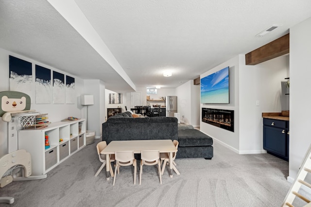 carpeted dining room with visible vents, a textured ceiling, baseboards, and a glass covered fireplace